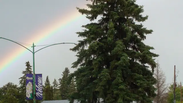Rainbow over town street with Welcome banners